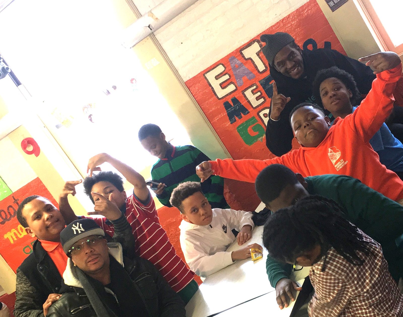 coach Dave and Barry sitting at a lunch room table at Brooklyn Landmark Elementary School during lunch recess, observing student social and behavioral patterns to help prevent violence.